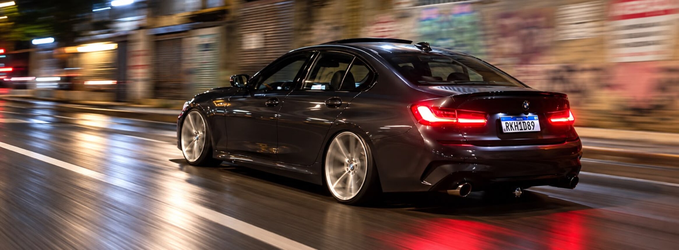 BMW 320i G20 cinza grafite rebaixada em movimento à noite - traseira